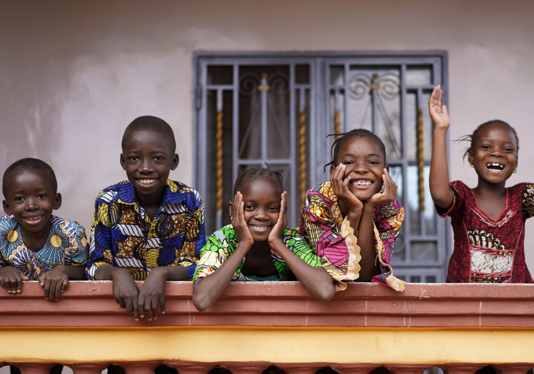 Five African Children Greeting Bypassers From A Colonial House Balcony